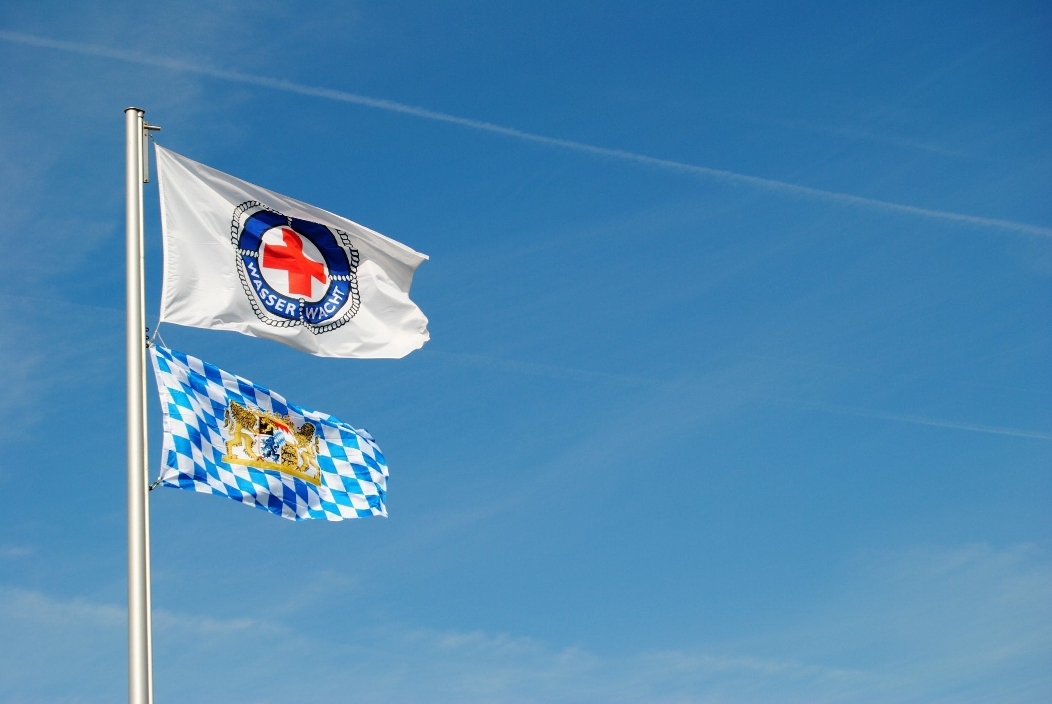 Flaggen der Wasserwacht und Bayern wehen im Himmel im Fünfseenland