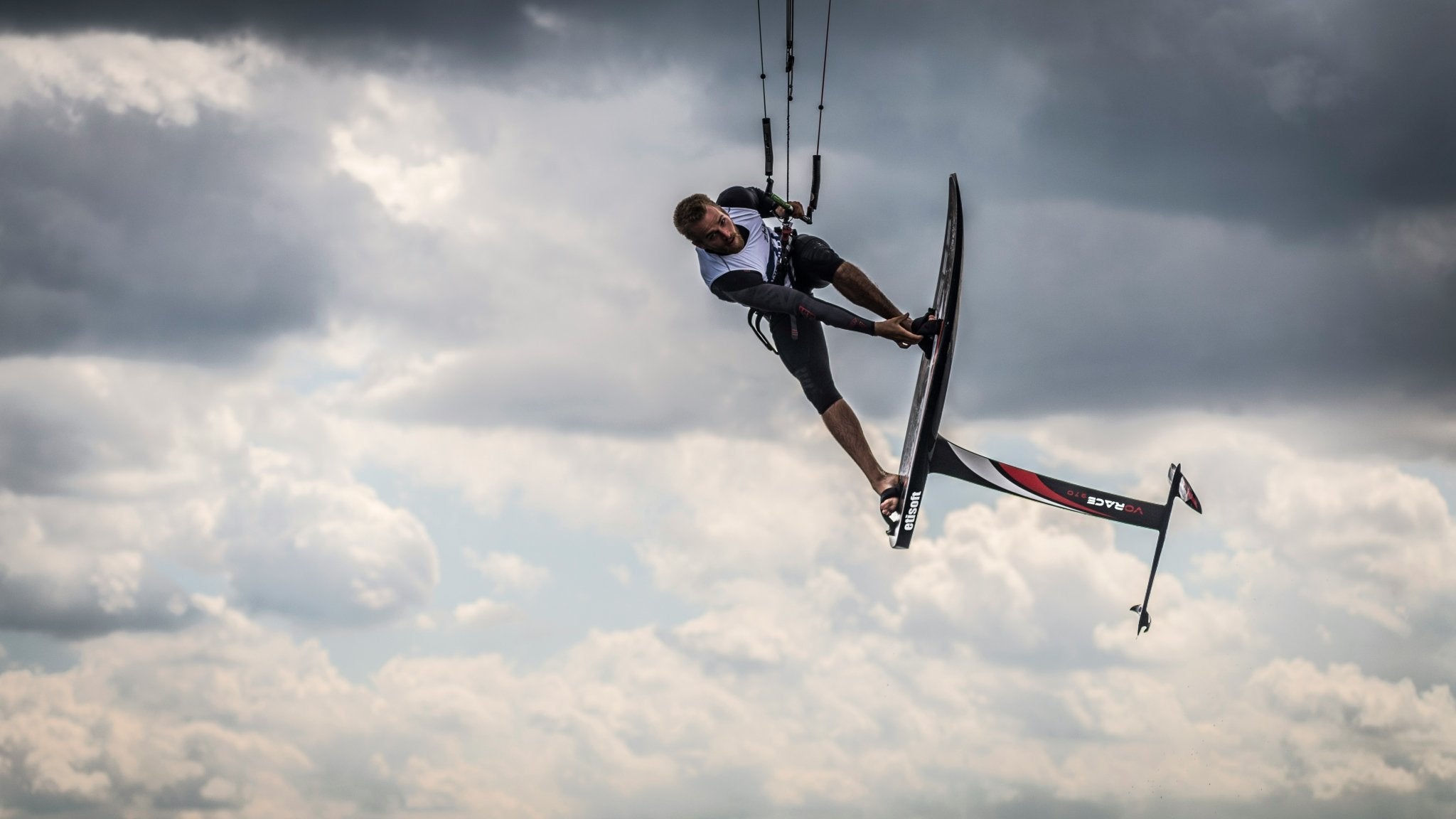 Mann beim Foilen (Wingfoil & Foil Surfen) am Kite in der Luft am Ammersee, Starnberger See & Wörthsee bei München & Augsburg